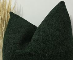 a green pillow sitting on top of a table next to a vase with dry grass in it