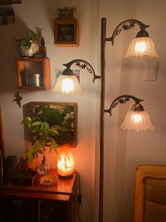 three lights that are next to each other on a wall near a table with a plant