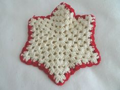 a red and white crocheted star dishcloth on a white table cloth,