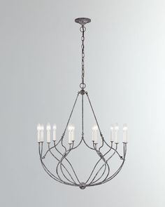 an iron chandelier with eight candles hanging from the center, on a gray background