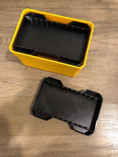 an empty yellow box sitting on top of a wooden table next to a black tray