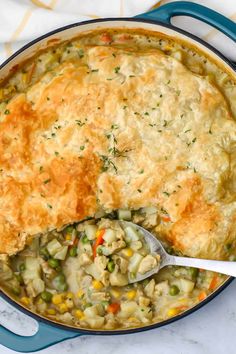 a pot filled with chicken pot pie on top of a white countertop next to a blue spatula