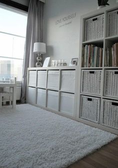 a living room with white furniture and lots of books on the bookcases in front of a large window