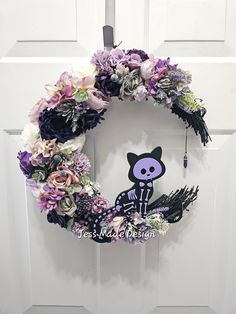 a purple and white wreath with a black cat on it's side hanging from the front door