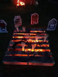 halloween decorations made out of pallets and lit up in the dark with hands on them