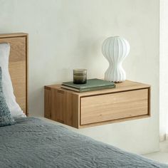 a nightstand with a book and candle on it next to a bed