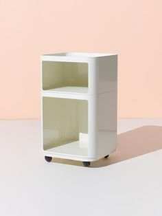 a small white shelf sitting on top of a table next to a pink and beige wall