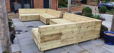 wooden benches sitting on top of a sidewalk next to a blue trash can in front of a brick building