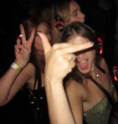 a group of young women standing next to each other holding up their fingers in the air