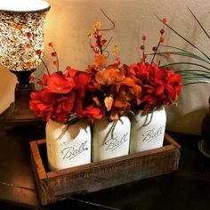 three jars with flowers in them sitting on a table