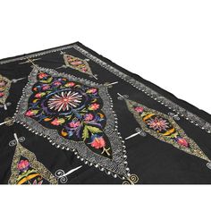 a black table cloth with multicolored flowers and ornate designs on the edges,