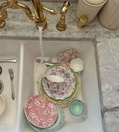 a sink filled with plates and cups next to a faucet