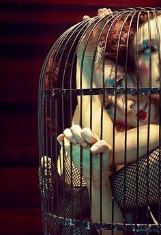 a woman is sitting in a cage with her hands on her chest