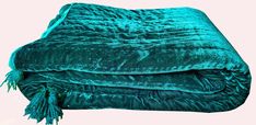 a green blanket with tassels is folded on top of each other in front of a white background