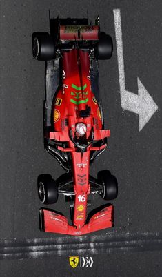 a red race car driving down a street with an arrow pointing to the left side