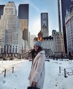 a woman is standing in the snow with her handbag