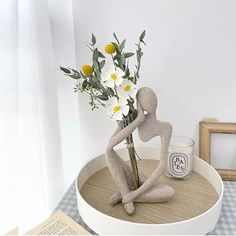 there is a vase with flowers in it and a statue on the table next to it