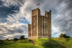 an old stone castle with a flag on top and stairs leading up to the tower