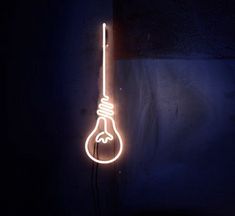 a neon light bulb hanging from the side of a wall in a dark room with a black background