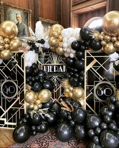 black, gold and white balloons are on display in front of an art deco backdrop