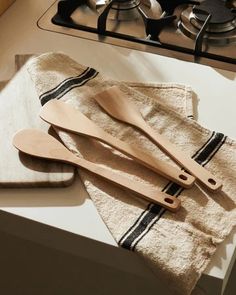 three wooden utensils sitting on top of a kitchen counter next to a towel