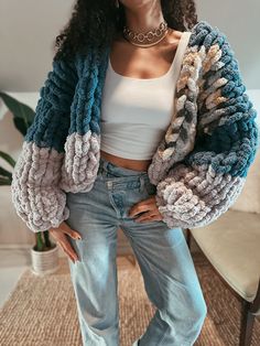 a woman standing in front of a chair with her hands on her hips wearing jeans and a crop top