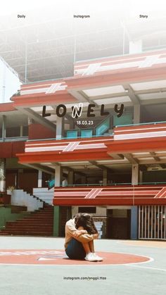 a woman sitting on the ground in front of a building with an advertisement for lonely