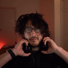 a man with long hair and glasses talking on a cell phone while wearing headphones