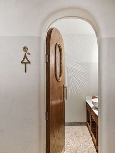 an arched doorway leading to a bathroom with a sink and mirror on the wall next to it