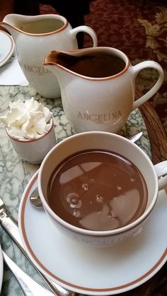 there is a cup of hot chocolate on the table with other cups and spoons