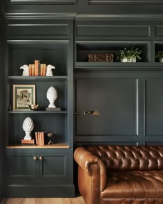 a brown leather couch sitting in front of a book shelf