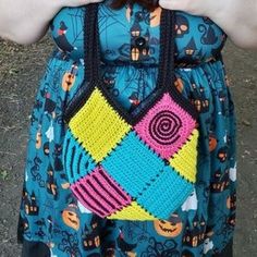 a crocheted bag is being held up by someone's hands and wearing it