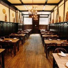 an empty dining room with wooden tables and chairs, chandelier hanging from the ceiling