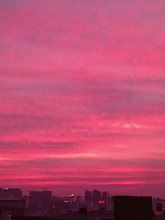 the sky is pink and purple with buildings in the background