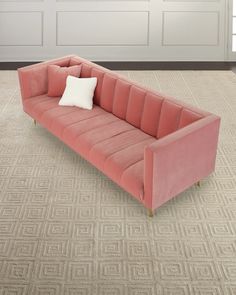 a pink couch sitting on top of a carpeted floor next to a white door