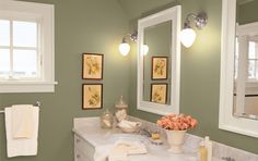 a bathroom with green walls and white counter tops, two mirrors on the wall above the sink