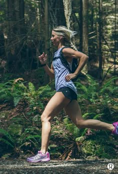 a woman running in the woods on a trail