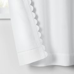 a white curtain with scalloped edges hanging in front of a window sill