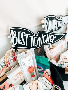 two black and white signs that say best teacher in front of some other items on the table