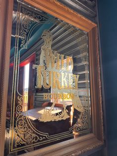 a mirror with the words wild turkey on it in gold lettering and an image of a man riding a horse