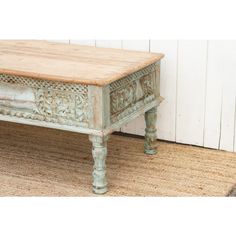 an old wooden table sitting on top of a rug next to a white wall and door