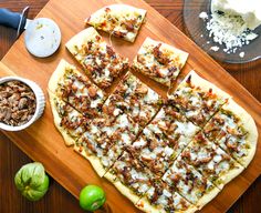 a wooden cutting board topped with pizza and toppings