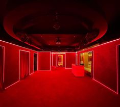 an empty room with red walls and lights on the ceiling is lit up by bright red lighting