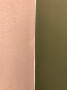 the corner of a room with a white toilet and green wall behind it is an open door