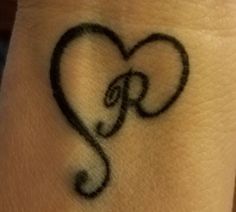 a small tattoo on the wrist of a person with a heart and letter r in it