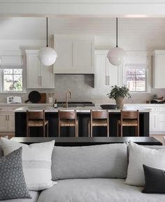 a living room filled with furniture and lots of white cupboards next to a kitchen