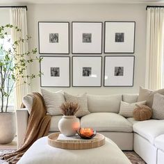 a living room filled with white furniture and pictures on the wall above it's coffee table