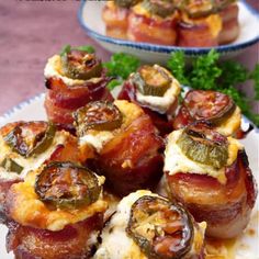 bacon wrapped in cheese and topped with green peppers on a white plate next to other food items