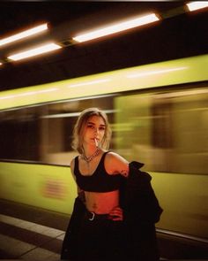 a woman standing in front of a train at night with her arm around her waist