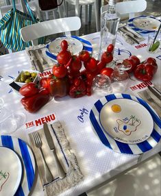 the table is set with plates, silverware and tomatoes